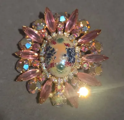 Sale Photo Thumbnail #43: Vintage gold-tone sunburst brooch featuring a speckled art glass cabochon center surrounded by pink marquise rhinestones and iridescent aurora borealis crystals.