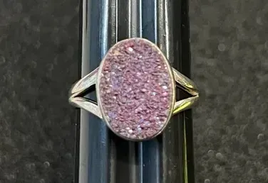 Sale Photo Thumbnail #14: Sterling silver ring featuring an oval pink druzy quartz gemstone with split shoulders, displayed on a ring sizer.