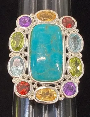 Sale Photo Thumbnail #118: Sterling silver statement ring featuring a large rectangular turquoise center cabochon framed by a halo of multi-colored faceted gemstones including peridot, garnet, amethyst, and topaz.