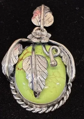 Sale Photo Thumbnail #97: Southwestern-style sterling silver and lime green turquoise pendant featuring detailed feather, flower, and scrollwork accents.