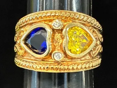 Sale Photo Thumbnail #120: Gold-tone wide band ring featuring heart-shaped blue and yellow stones accented with round clear stones and rope border details.