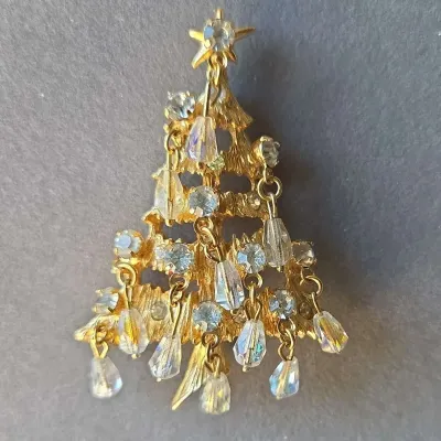 Sale Photo Thumbnail #41: Vintage gold-tone Christmas tree brooch embellished with clear rhinestone accents and dangling iridescent crystal bead ornaments.