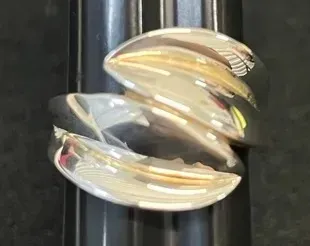 Sale Photo Thumbnail #16: Modernist sterling silver bypass ring featuring a polished, sculptural claw-like design displayed on a ring sizer mandrel.
