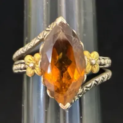 Sale Photo Thumbnail #11: Marquise-cut amber or citrine stone ring featuring textured silver bands and gold-tone floral accents on each side.