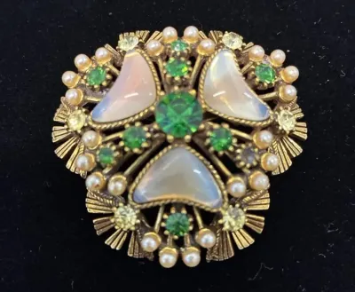 Sale Photo Thumbnail #73: Vintage gold-tone brooch featuring pearlescent cabochons, green rhinestones, and faux pearls in an ornate, textured setting.