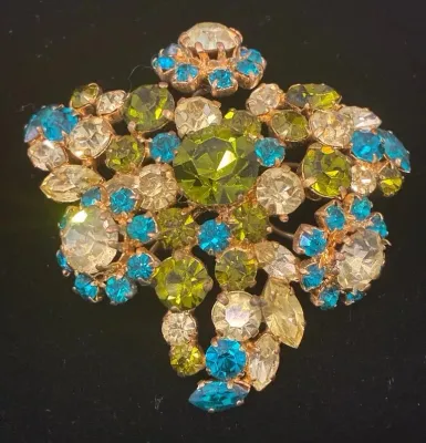 Sale Photo Thumbnail #88: Vintage gold-tone floral rhinestone brooch featuring olive green, turquoise blue, and clear sparkling faceted stones.