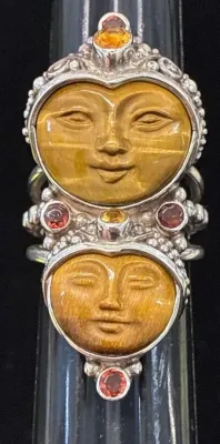 Sale Photo Thumbnail #110: Intricately detailed sterling silver ring featuring two carved tiger's eye moon faces accented with bezel-set garnet and citrine gemstones.
