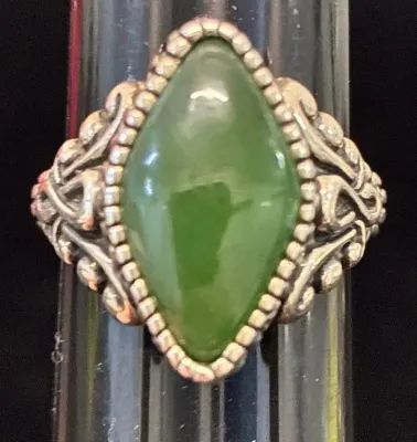 Sale Photo Thumbnail #77: Vintage sterling silver ring set with a marquise-cut green jade cabochon, featuring a beaded bezel border and ornate scrollwork shoulders.