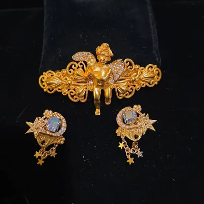 Sale Photo Thumbnail #23: Gold-tone cherub brooch with filigree and rhinestones, alongside a pair of celestial crescent moon and star clip-on earrings with dangles.