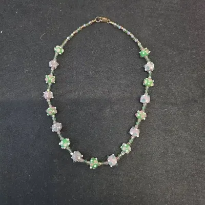 Sale Photo Thumbnail #63: Handcrafted lampwork glass bead necklace featuring green and mauve dotted beads strung with small iridescent accent beads and a barrel clasp.