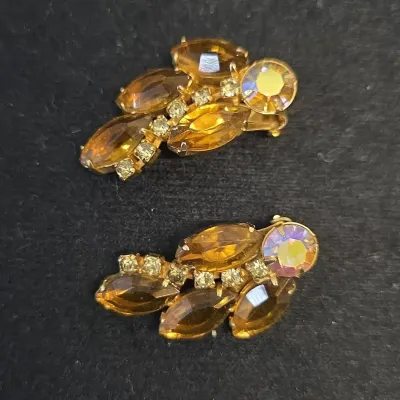 Sale Photo Thumbnail #39: Vintage gold-tone clip-on costume earrings featuring amber navette cut stones and aurora borealis accents.