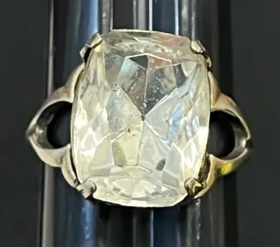 Sale Photo Thumbnail #115: Vintage silver-tone cocktail ring featuring a large cushion-cut clear glass stone set in a four-prong mounting.