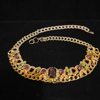 Sale Photo Thumbnail #26: Vintage gold-tone chain necklace set with purple and green rhinestones, featuring an emerald-cut central stone.