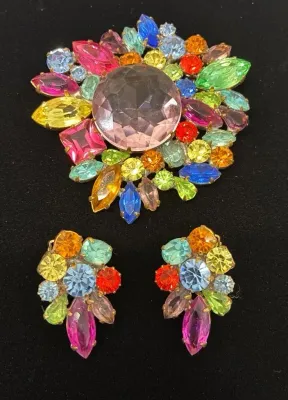 Sale Photo Thumbnail #76: Vintage multicolor rhinestone jewelry set featuring a large brooch with a center pink stone and matching clip-on earrings.