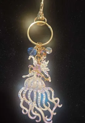 Sale Photo Thumbnail #34: Gold-tone keychain featuring an enamel and rhinestone fairy charm with iridescent bead accents.
