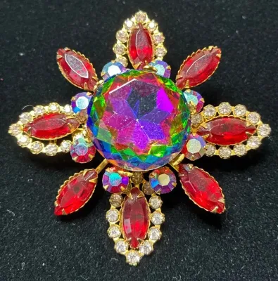 Sale Photo Thumbnail #56: Vintage gold-tone starburst brooch featuring a large center iridescent watermelon rhinestone surrounded by red marquise and clear aurora borealis rhinestones.