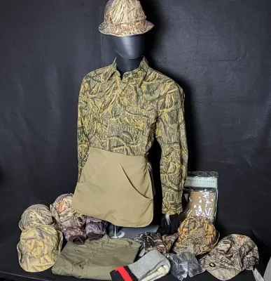Collection of camouflage hunting gear displayed on a mannequin, including a Cabela's long-sleeve shirt, bucket hat, half apron,...