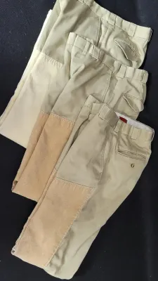 Set of three pairs of vintage men's khaki hunting pants featuring reinforced suede leg panels and flap back pockets.