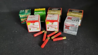 Collection of .410 bore shotgun shell boxes, including Winchester Super Speed, Remington, Estate, and Federal, accompanied by loose red...