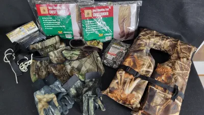 Collection of outdoor hunting and fishing gear, including camouflage life jackets, gloves, RedHead accessories, a Stearns poncho, and...