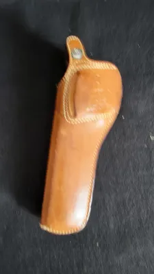Vintage tan leather handgun holster featuring contrast perimeter stitching and a snap-closure retaining strap.