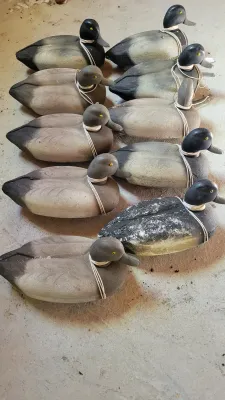 Collection of nine molded plastic duck decoys with painted details and attached string ties. Items show varying degrees of surface wear...