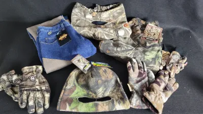 Collection of camouflage outdoor gear including hunting gloves, face masks, a beanie, pants, and Guide Gear denim trousers with attached...