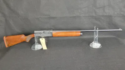 Browning Auto-5 semi-automatic shotgun with a checkered wood stock and forend, displayed on clear acrylic stands.