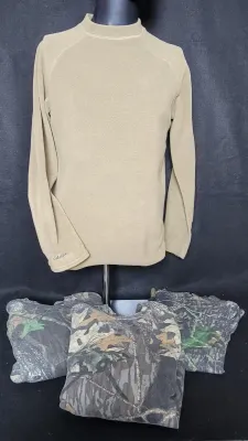 Men's tan Cabela's fleece long-sleeve thermal shirt displayed on a mannequin with folded camouflage garments below.