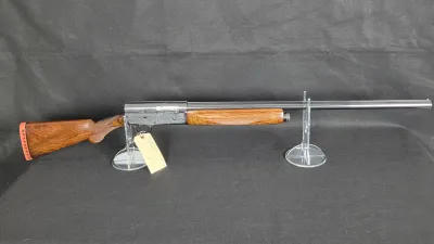 Vintage Remington Model 11 semi-automatic shotgun with engraved receiver and wooden stock on clear acrylic display stands.