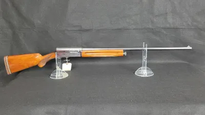 Browning Auto-5 semi-automatic shotgun with checkered wood stock and forend, displayed on clear acrylic stands.