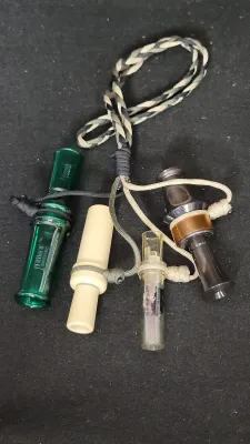 Collection of four game calls attached to a camouflage braided lanyard, including a green Primos hunting call.