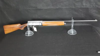 Browning Auto-5 semi-automatic shotgun with a checkered wooden stock and forend, displayed on clear acrylic stands.