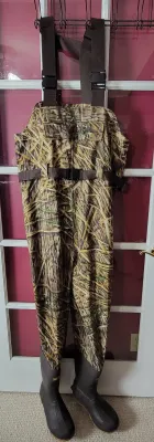 Realtree camouflage chest waders with integrated rubber boots and adjustable shoulder straps.