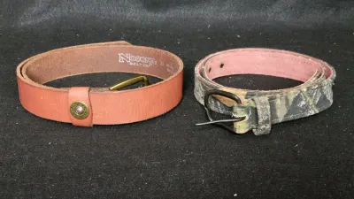 Two leather belts including a size 32 Nocona Belt Co. leather belt with a 12-gauge shotgun shell detail and a camouflage fabric-lined...