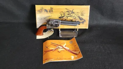 A. Uberti miniature single-action revolver replica with wooden grip, complete with its original presentation box and booklet.
