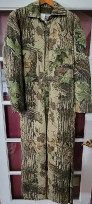 Vintage Walls Outdoor Goods insulated camouflage hunting jumpsuit, hanging on a door frame.