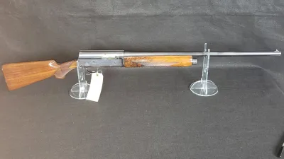 Browning Auto-5 semi-automatic shotgun with checkered wood stock and forend, displayed on clear acrylic stands.