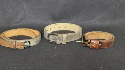 Trio of men's outdoor and hunting belts, including camouflage patterns and a leather belt featuring a brass flying duck detail on...