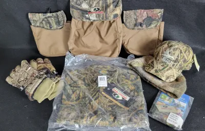 Collection of camouflage hunting gear, including a Mossy Oak game belt with pouches, a packaged Cabela's shirt, gloves, a Delta...