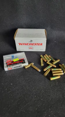 Collection of ammunition including a Winchester cartridge box, a plastic case of CCI 38/357 shotshells, and loose brass handgun rounds.