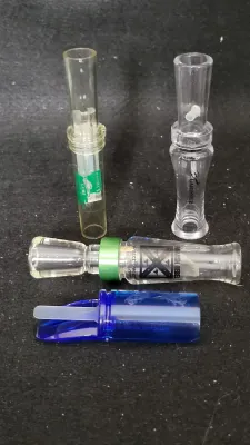 Collection of four acrylic game calls, including Buck Gardner and Waterfowl calls in clear and blue plastic.