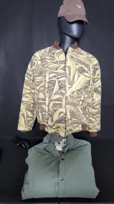 Vintage cornstalk camouflage bomber jacket displayed on a mannequin with a brown baseball cap, accompanied by a folded green snap-front...
