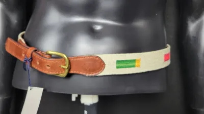 Canvas and leather belt featuring colorful embroidered shotgun shell motifs with a brass buckle, displayed on a mannequin torso.
