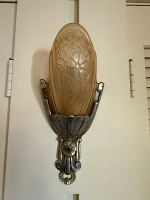 Sale Photo Thumbnail #416: Art Deco wall sconce featuring molded frosted amber glass with floral motifs and an ornate metal bracket, circa 1930s.