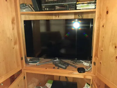 Sale Photo Thumbnail #108: Samsung flat screen television set inside a light wood entertainment armoire with remotes and audio equipment.