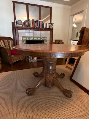 Sale Photo Thumbnail #166: Round oak pedestal dining table featuring carved claw feet and a thick pedestal base.