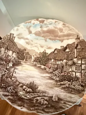 Sale Photo Thumbnail #408: Vintage transferware decorative ceramic plate featuring a hand-tinted English village scene with thatched cottages and a scalloped rim.