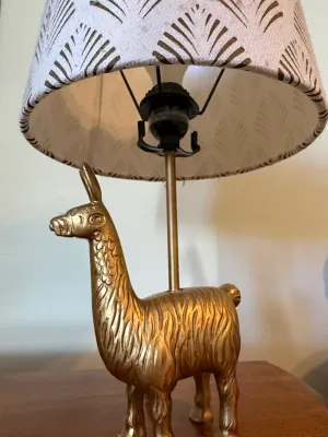 Sale Photo Thumbnail #366: Novelty table lamp featuring a textured gold-tone llama base and a fabric shade with a gold fan pattern.