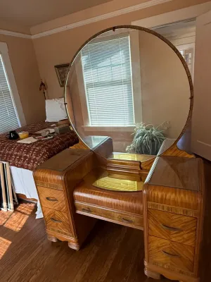 Sale Photo Thumbnail #255: Art Deco waterfall vanity with a large round mirror, featuring veneer inlay, brass hardware, and glass tops.